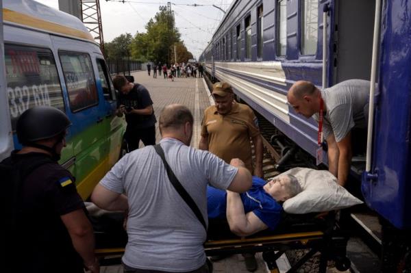 Volunteers of the East SOS evacuation organisation lift a woman onto an evacuation train as local residents flee Russian troop advances in Pokrovsk, Ukraine, amid Russia's attack on Ukraine, August 22, 2024. REUTERS/Thomas Peter